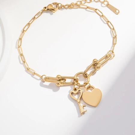 Bracciale dorato con catena regolabile e ciondoli a forma di cuore e chiave in acciaio.